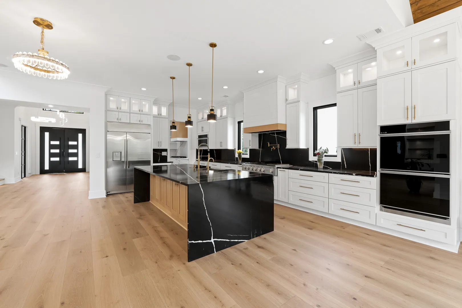 Kitchen at 3610 Sky Lane with a black marble waterfall island, brass pendants and white cabinetry